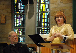 As the dean of the Terre Haute Deanery, Father Rick Ginther, left, listens during a July 14 press conference as Ann Ryan explains some of the changes that will result from a strategic plan to revitalize the Church in west central Indiana. Ryan is the communication chairperson of the Terre Haute Deanery Strategic Plan. (Photo by John Shaughnessy)