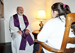 Father Clement Davis, pastor of St. Bartholomew Parish in Columbus, prepares to celebrate the sacrament of penance with a student of St. Rose of Lima School on Dec. 6, 2012, in a confessional at St. Rose of Lima Church in Franklin. (File photo by Sean Gallagher)