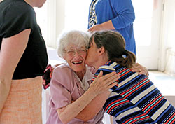 Lesley Bartone, administrative coordinator for the Office of Mission and Ministry at Marian University in Indianapolis, gives a kiss to Franciscan Sister Norma Rocklage on July 15 in Marian’s Allison Mansion during a farewell reception for Sister Norma, who retired after nearly 30 years of ministry at the school. She was also at Marian from 1965-74, teaching Latin and Greek and serving as academic dean. (Submitted photo)