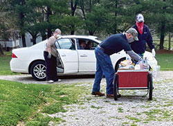 Ryan Borden, middle, and Nick Kleaving, left, both members of the Knights of Columbus of St. Isidore the Farmer Parish in Perry County, help fellow parishioner Ramona Gehlausen, manager of the parish’s Martin’s Cloak ministry, distribute food on May 2 at the the parish’s St. Martin campus in Siberia. (Submitted photo)