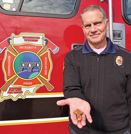 In this Oct. 16 photo outside a fire station in Avon, Deacon Jerome Bessler, a battalion chief for Washington Township Avon Fire Department, displays one of the pocket crosses he carries with him on emergency runs to share with those impacted who might find it helpful. (Photo by Natalie Hoefer)